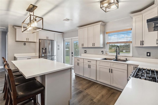 kitchen featuring sink, appliances with stainless steel finishes, white cabinetry, hanging light fixtures, and a kitchen island