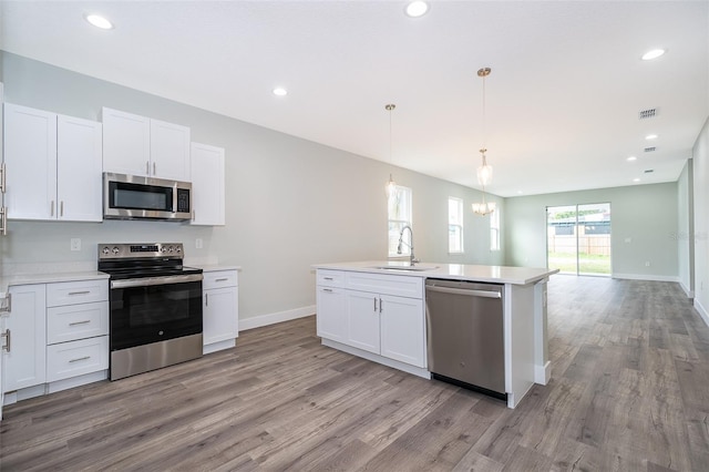 kitchen with white cabinets, stainless steel appliances, and decorative light fixtures