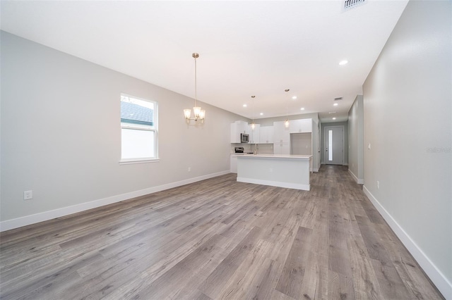 unfurnished living room with a notable chandelier and light wood-type flooring