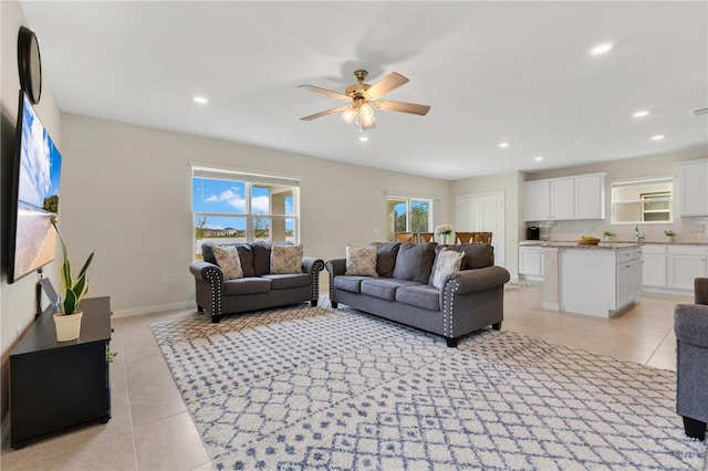 tiled living room featuring sink, ceiling fan, and plenty of natural light