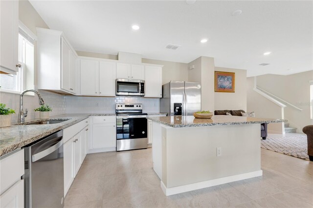 kitchen featuring sink, light stone counters, white cabinetry, and stainless steel appliances