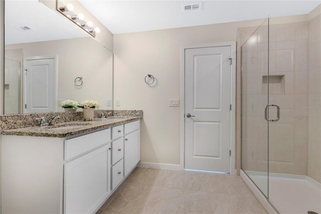 bathroom with tile patterned flooring, a shower with door, and vanity