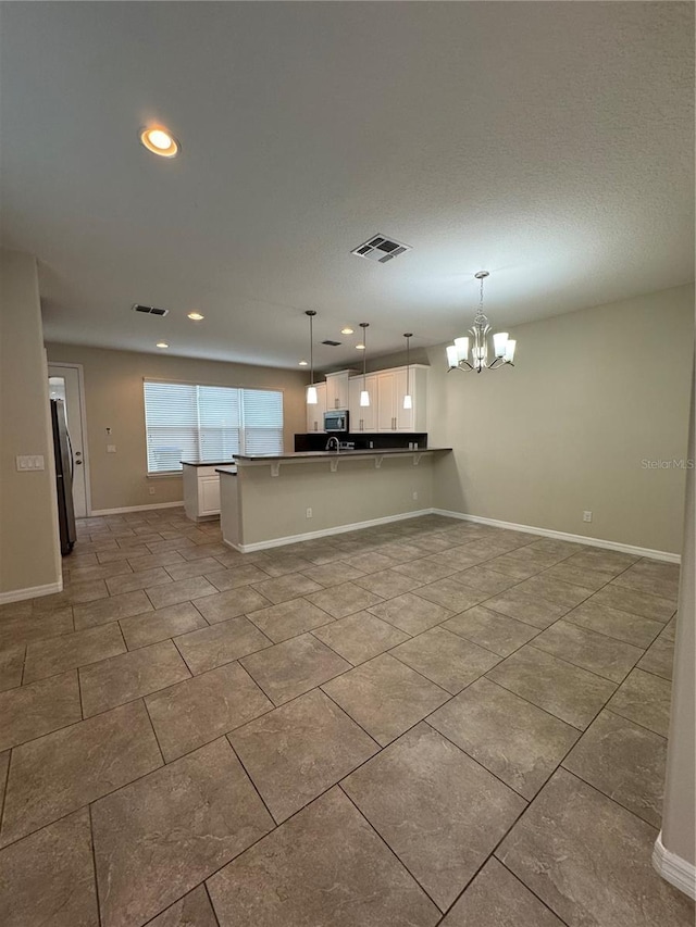 kitchen with kitchen peninsula, decorative light fixtures, a breakfast bar, white cabinets, and appliances with stainless steel finishes