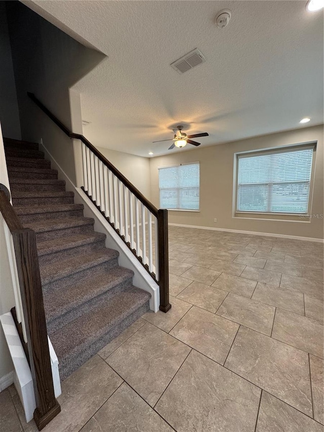 staircase featuring ceiling fan and a textured ceiling