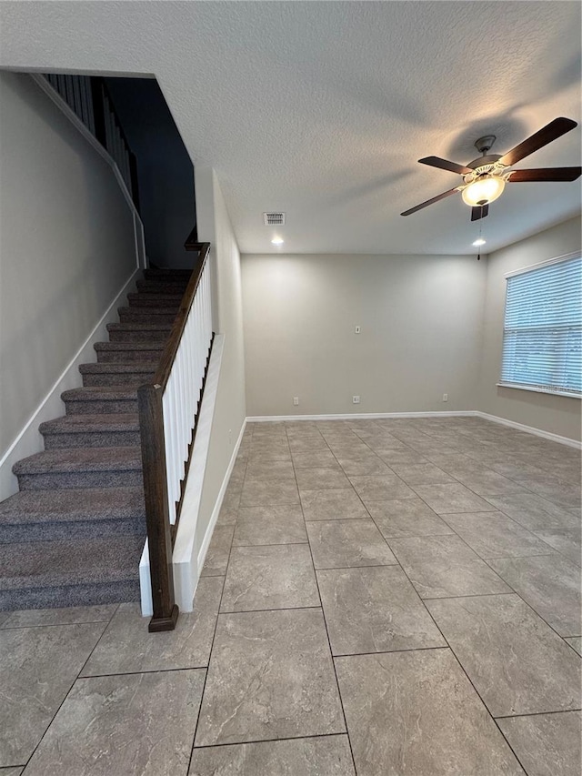 stairway with a textured ceiling and ceiling fan