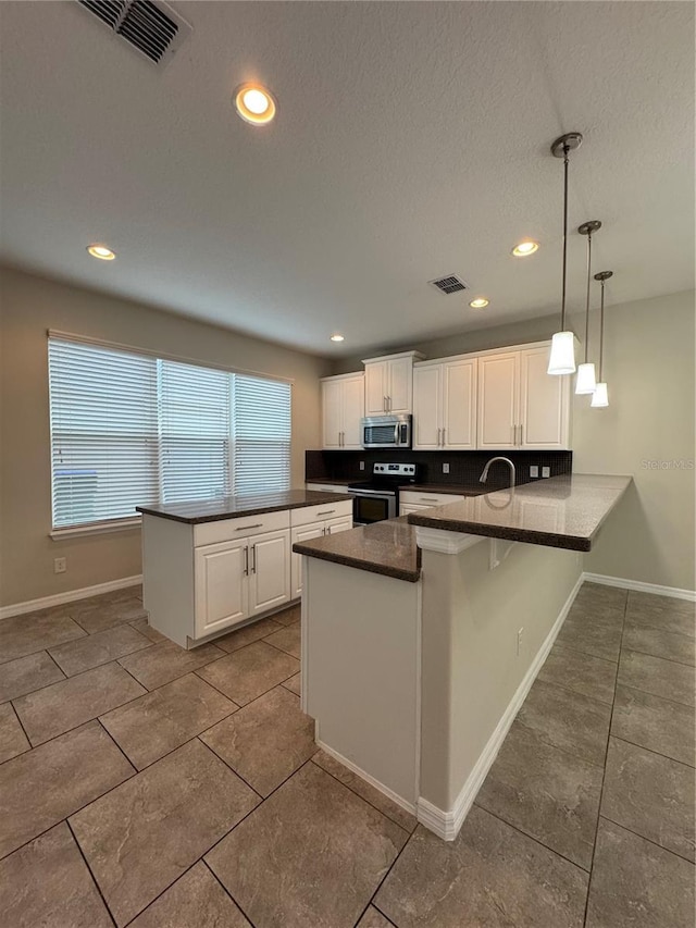 kitchen featuring a kitchen breakfast bar, kitchen peninsula, decorative light fixtures, white cabinets, and appliances with stainless steel finishes