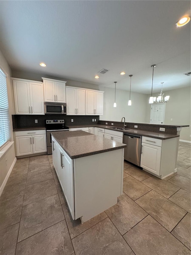 kitchen with a center island, stainless steel appliances, white cabinetry, and hanging light fixtures