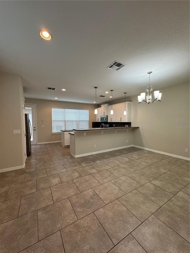 kitchen featuring kitchen peninsula, appliances with stainless steel finishes, a breakfast bar, pendant lighting, and white cabinetry