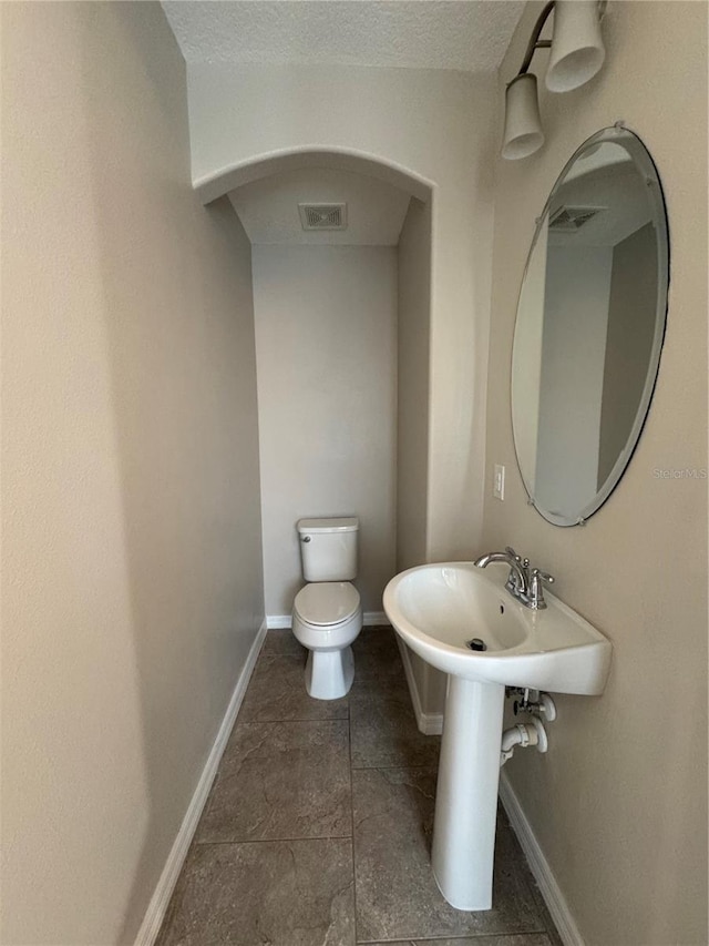 bathroom with tile patterned flooring, toilet, and a textured ceiling