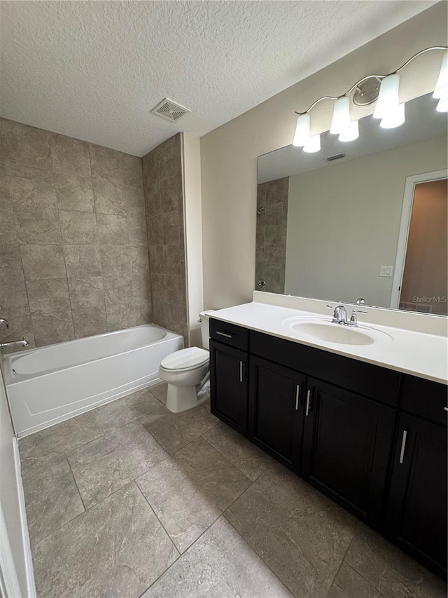 full bathroom featuring a textured ceiling, vanity, toilet, and tiled shower / bath combo