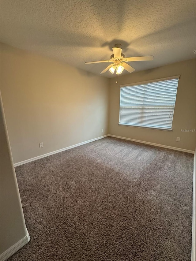 unfurnished room featuring ceiling fan, dark carpet, and a textured ceiling