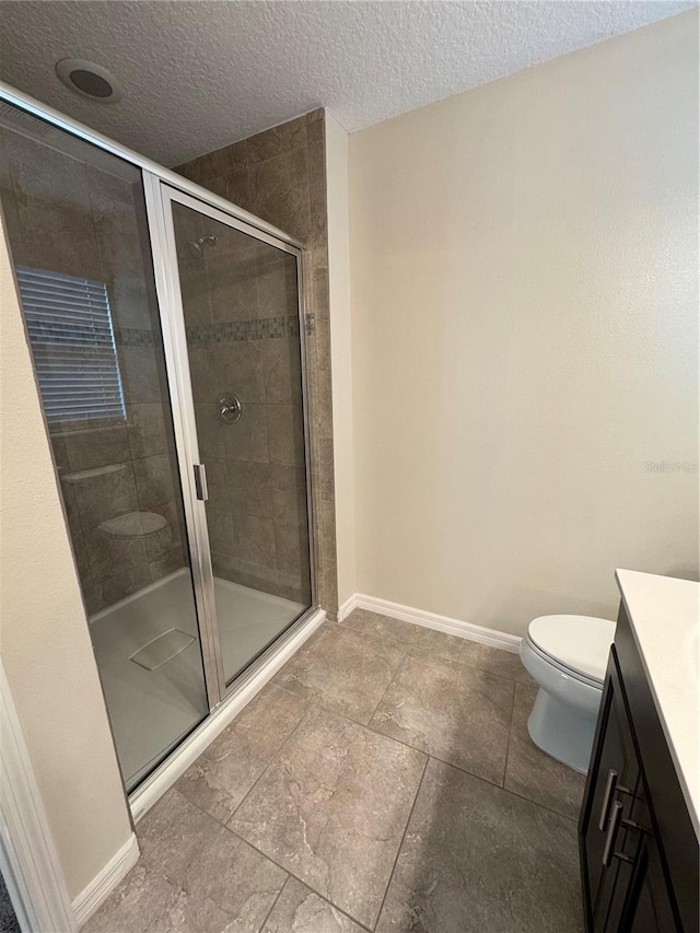 bathroom with a textured ceiling, vanity, toilet, and a shower with shower door