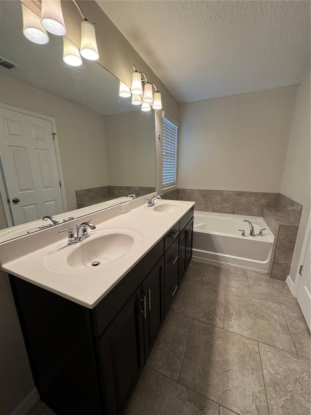 bathroom featuring a bathing tub, vanity, and a textured ceiling