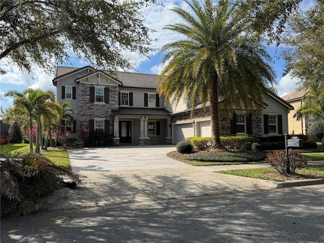 view of front of home with metal roof, an attached garage, stone siding, decorative driveway, and a standing seam roof