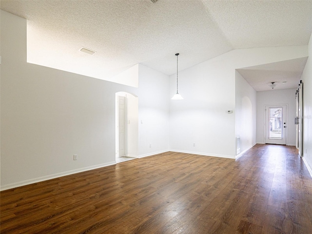 unfurnished room featuring a textured ceiling, lofted ceiling, and dark hardwood / wood-style floors