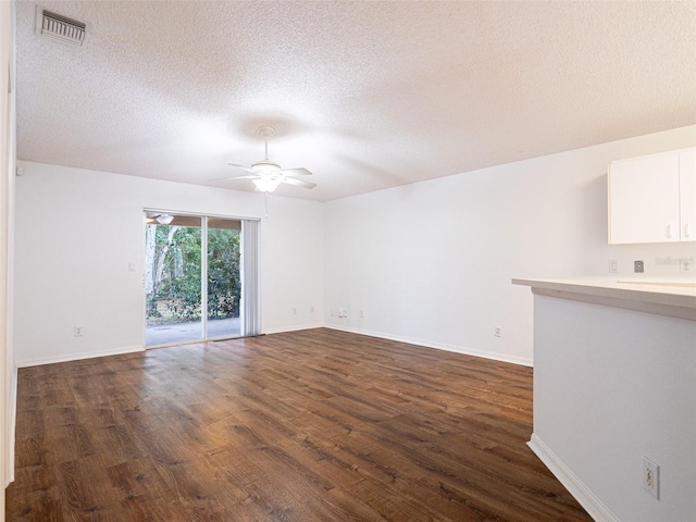 empty room with a textured ceiling, dark wood-type flooring, and ceiling fan