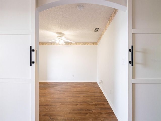 empty room with ceiling fan, a textured ceiling, and hardwood / wood-style flooring