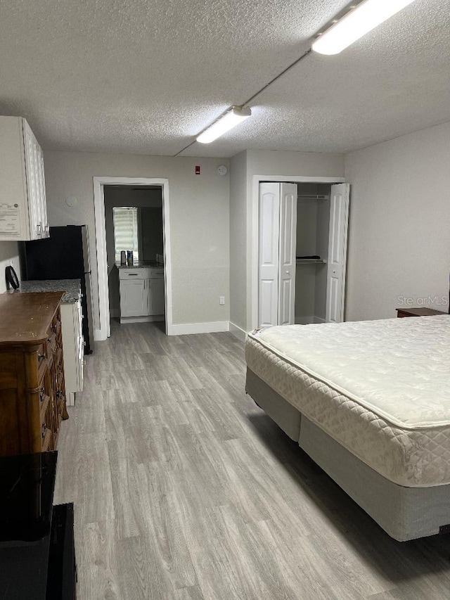 bedroom with light hardwood / wood-style flooring, a textured ceiling, and a closet