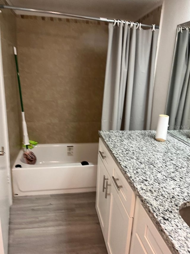 bathroom with hardwood / wood-style floors, vanity, and shower / bath combo