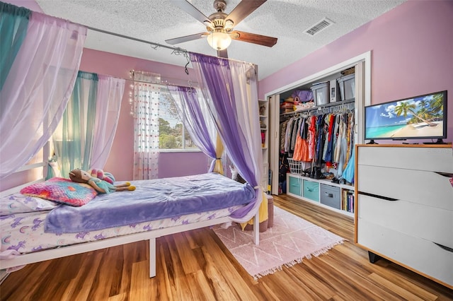 bedroom with ceiling fan, a closet, a textured ceiling, and hardwood / wood-style flooring