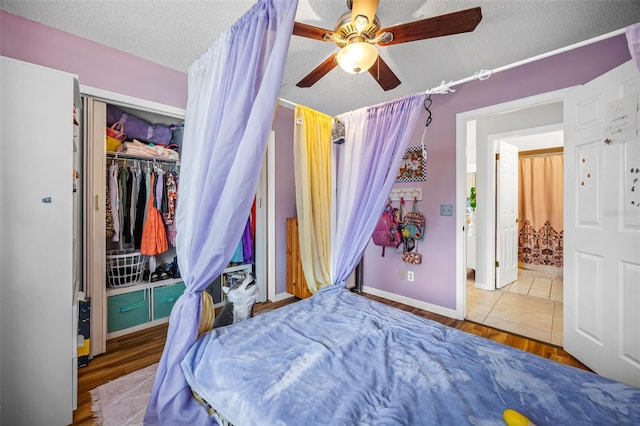 bedroom with hardwood / wood-style flooring, ceiling fan, a textured ceiling, and a closet