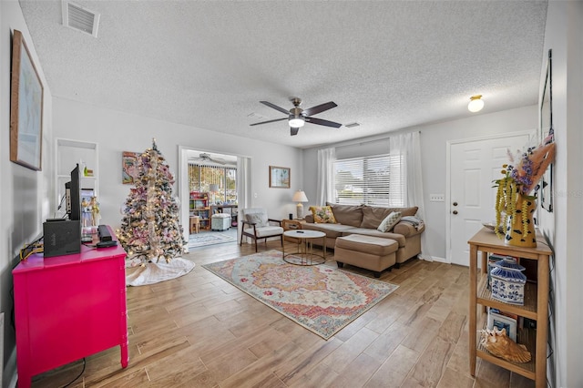 living room with a textured ceiling, hardwood / wood-style flooring, and ceiling fan