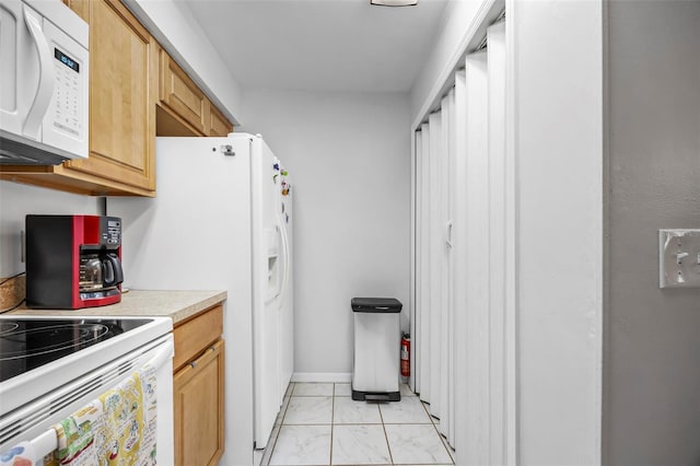 kitchen featuring light brown cabinetry and white appliances