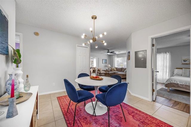 tiled dining room with ceiling fan with notable chandelier and a textured ceiling