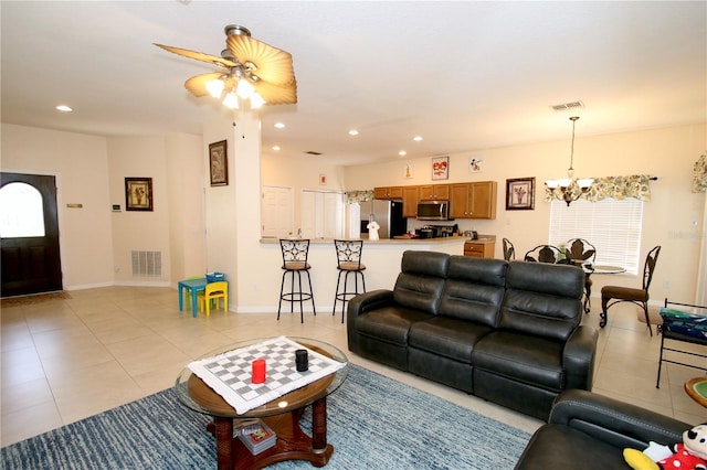 living room with ceiling fan with notable chandelier and light tile patterned floors