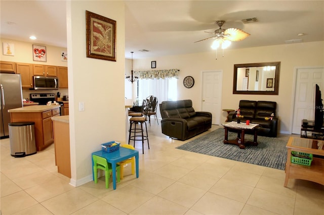 living room with ceiling fan with notable chandelier and light tile patterned floors