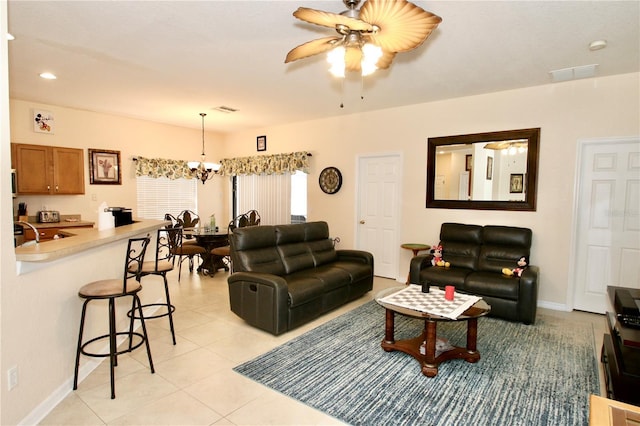 tiled living room with ceiling fan with notable chandelier