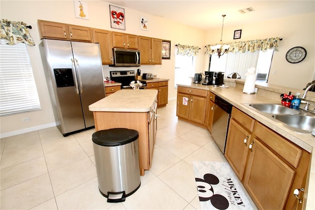 kitchen with stainless steel appliances, sink, a center island, a chandelier, and pendant lighting