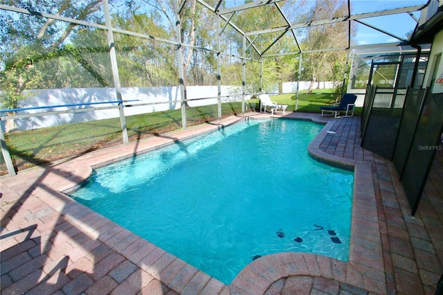 view of pool with a lanai, a patio area, and a lawn