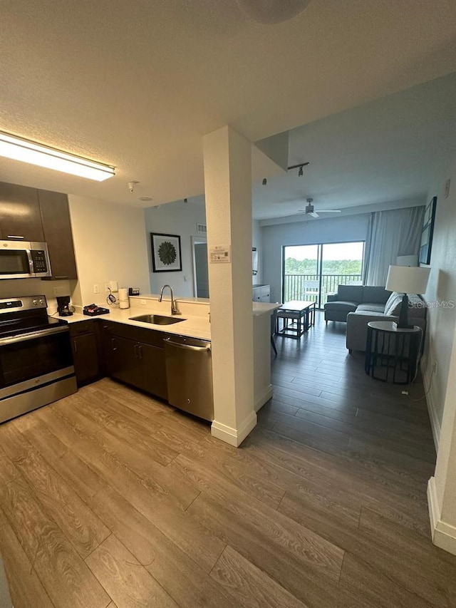 kitchen featuring sink, light hardwood / wood-style flooring, appliances with stainless steel finishes, kitchen peninsula, and ceiling fan