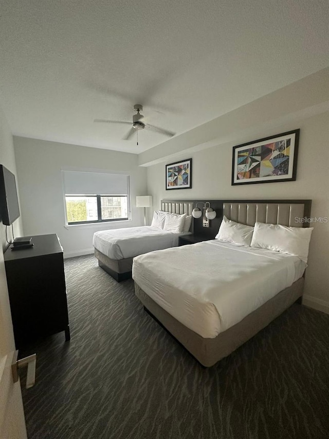 bedroom with a textured ceiling, ceiling fan, and dark colored carpet