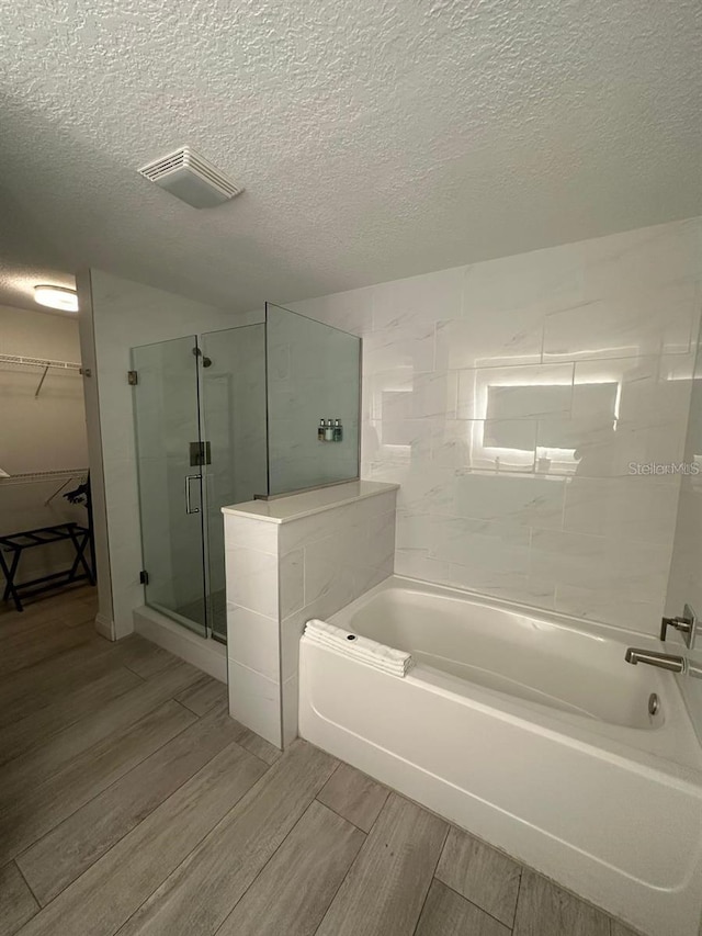 bathroom with separate shower and tub and a textured ceiling