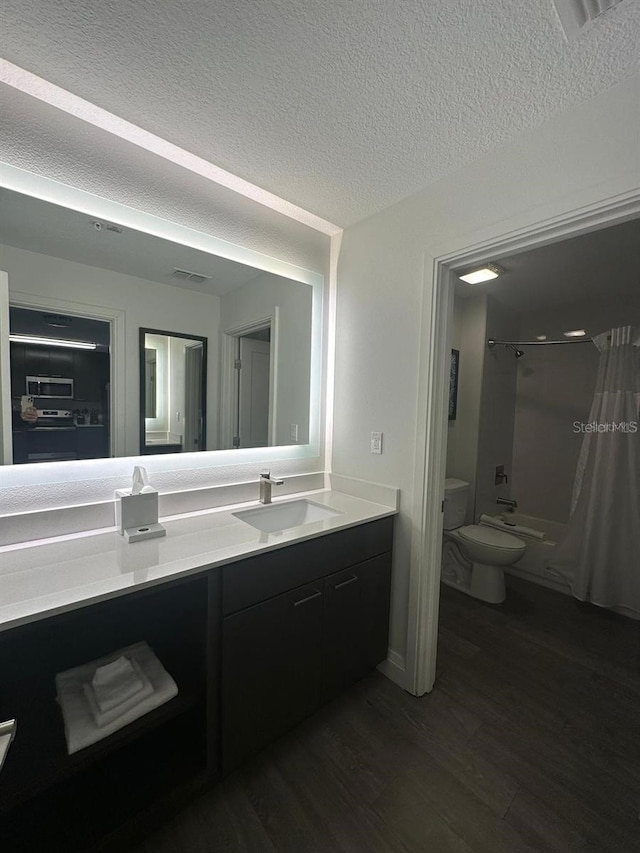 full bathroom featuring hardwood / wood-style floors, shower / tub combo with curtain, vanity, toilet, and a textured ceiling