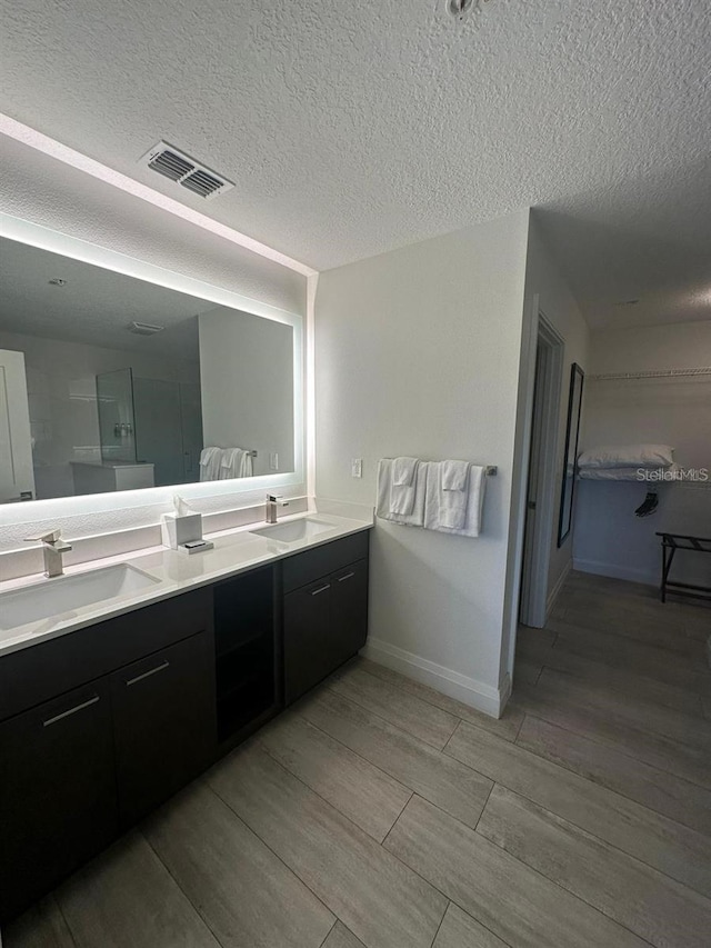 bathroom with vanity, an enclosed shower, and a textured ceiling