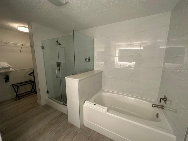 bathroom with shower with separate bathtub and a textured ceiling