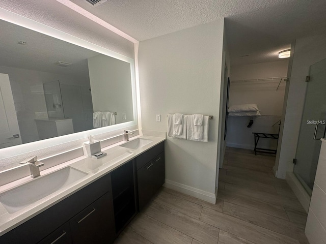 bathroom featuring vanity, an enclosed shower, and a textured ceiling