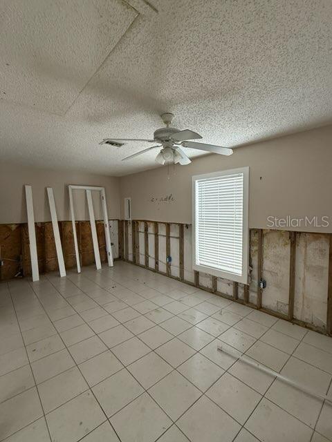 empty room with a textured ceiling and ceiling fan