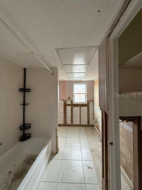 bathroom featuring washtub / shower combination and a textured ceiling