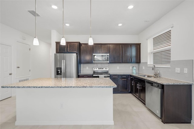 kitchen with hanging light fixtures, sink, a kitchen island, and stainless steel appliances