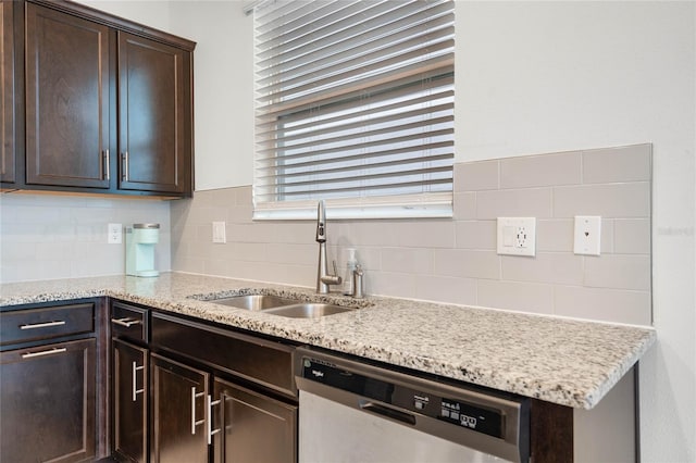 kitchen featuring sink, light stone counters, stainless steel dishwasher, backsplash, and dark brown cabinets