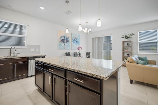 kitchen with dark brown cabinetry, sink, stainless steel dishwasher, decorative light fixtures, and a kitchen island