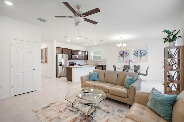 tiled living room with ceiling fan with notable chandelier