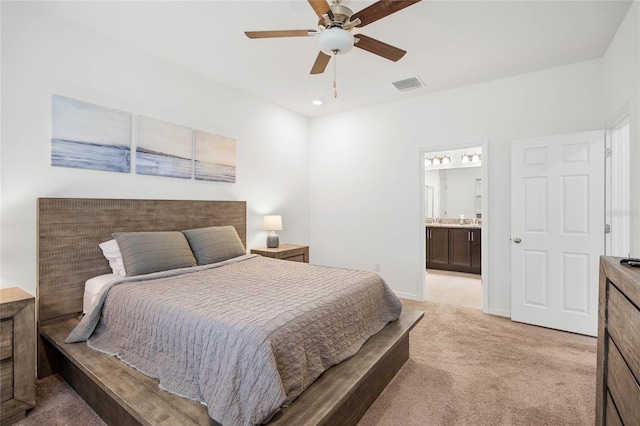 carpeted bedroom with ensuite bath and ceiling fan