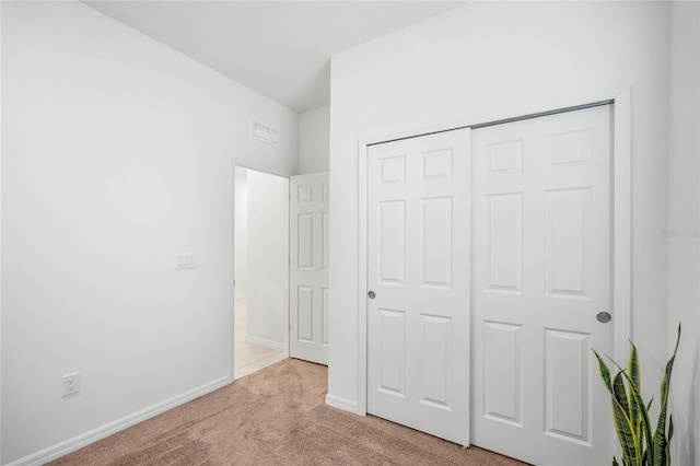 unfurnished bedroom featuring a closet and light colored carpet