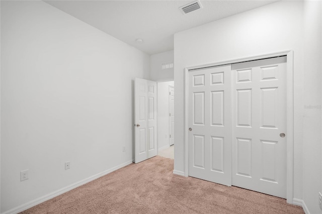 unfurnished bedroom with light colored carpet and a closet