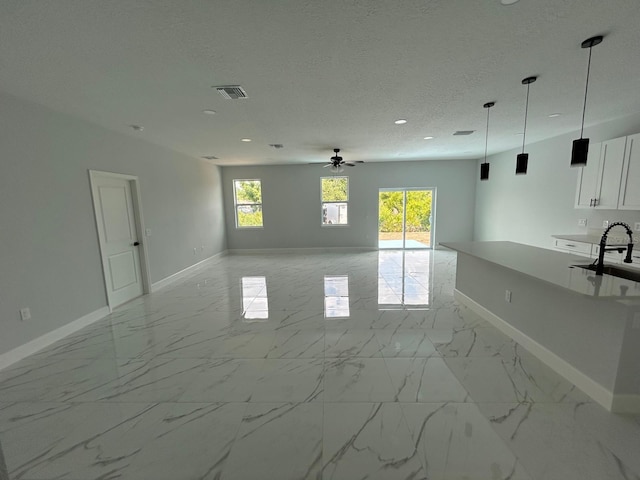 interior space with ceiling fan, sink, and a textured ceiling